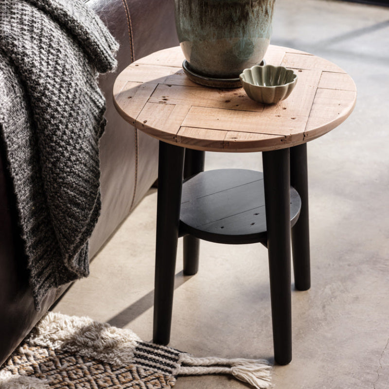 Round wooden side table with black legs on a white background