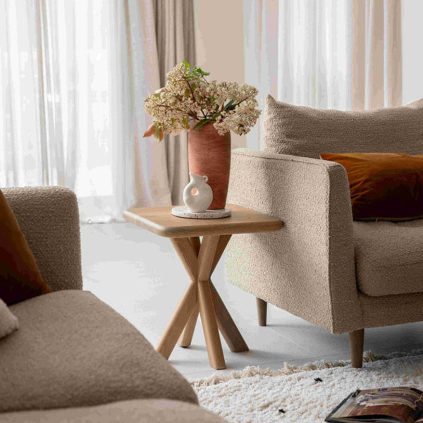 Cozy living room with beige sofa, wooden side table, and floral arrangement.