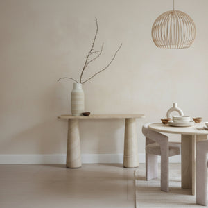 Minimalist interior with a stone table and vase against a plain wall.