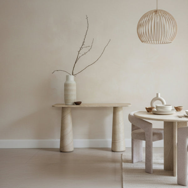 Minimalist interior with a stone table and vase against a plain wall.