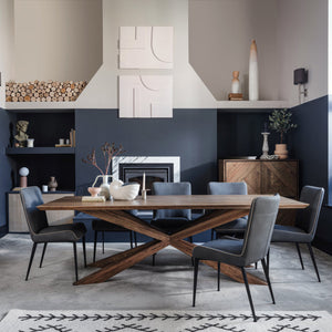 Modern dining room with wooden table and gray chairs against a dark blue wall.