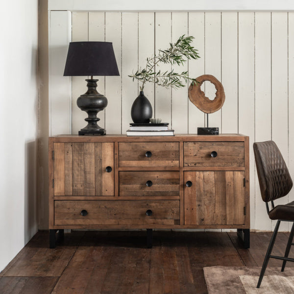 Wooden sideboard with decorative items against a white paneled wall.