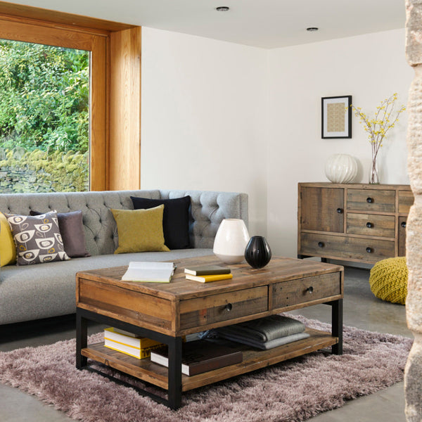 Modern living room with a gray sofa, wooden coffee table, and large window.