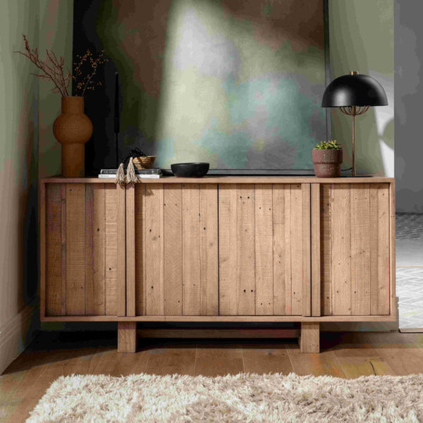 Wooden sideboard with decorative items in a room with abstract wall art.
