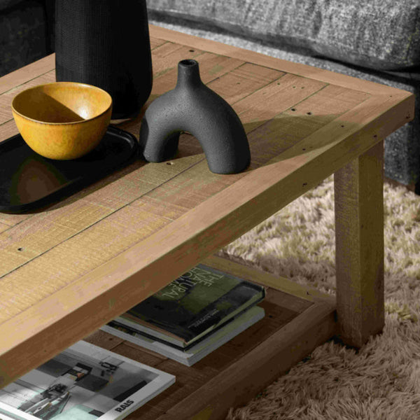 Wooden coffee table with decorative items including a bowl, vase, and books on a carpeted floor.