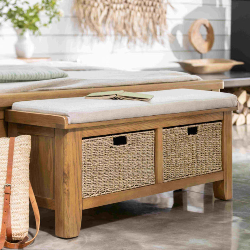 Wooden bench with white cushion and two wicker storage baskets on a white background