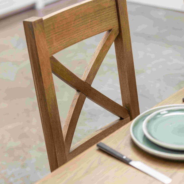 Wooden chair at a dining table with plates and cutlery on a patterned floor.