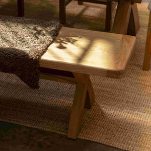 Wooden dining bench with a table on a textured rug