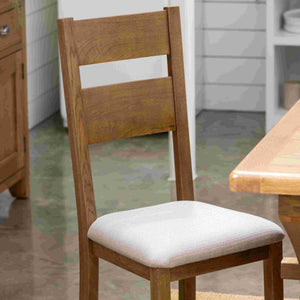 Wooden chair with a white cushion on a wooden floor.