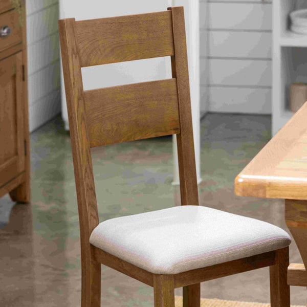 Wooden chair with a white cushion on a wooden floor.